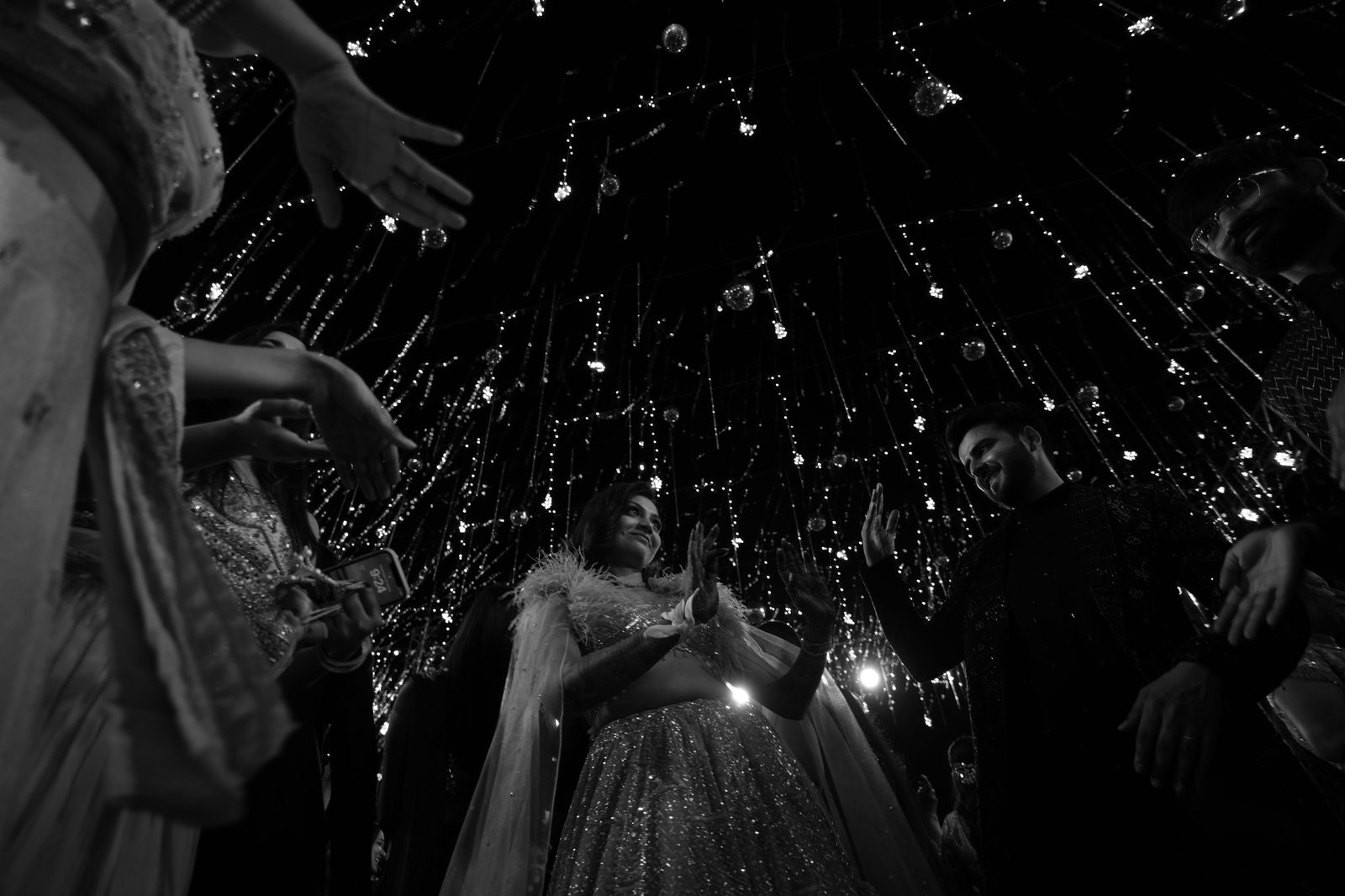 Bride beneath a crystal chandelier installation, in black and white